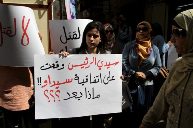 Protest op International Women's Day. De tekst op het bord: 'Meneer de president, u tekende het Verdrag inzake de uitbanning van alle vormen van discriminatie van vrouwen. Wat nu?!'