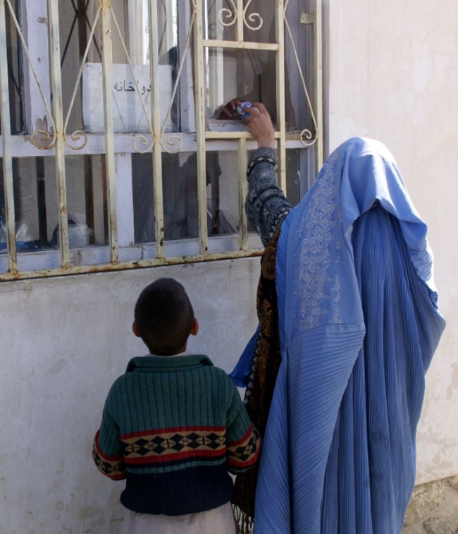 Een vrouw en kind krijgen een fles voedingssupplement door een gebroken raam van een kliniek in Afghanistan - http://www.directrelief.org/