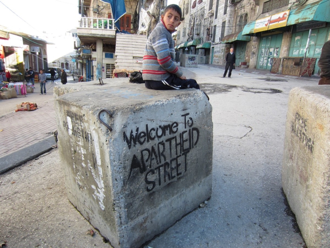 Straatbeeld van Hebron, rechts de souq, al jaren gesloten ter bescherming van een handvol kolonisten. ©Foto Travel to Palestine/Wikimedia Commons 