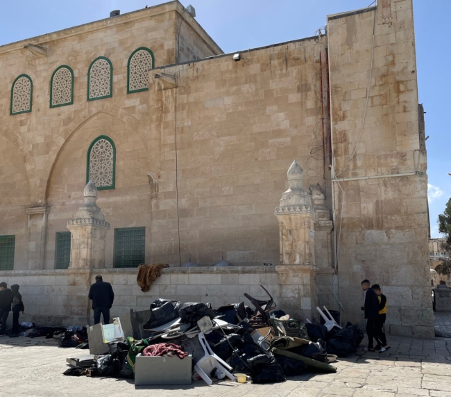 Mannen ruimen de overblijfselen van de inval in de Al-Aqsa moskee op.